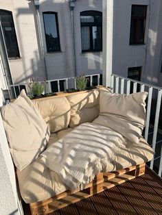 a couch made out of wooden pallets on a deck with pillows and plants in it