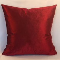 a red pillow sitting on top of a white bed