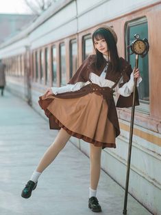 a woman in a brown and white dress leaning against a wall with a clock on it