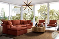 a living room with red couches and chairs in front of large windows overlooking trees