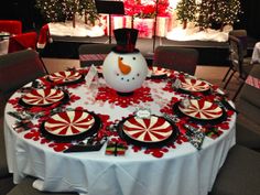 a snowman sitting on top of a table covered in plates and candy canes