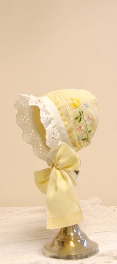 a yellow bonnet with white lace on it and a ribbon tied around the brim