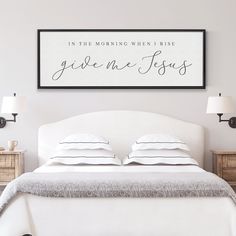 a white bed sitting under a framed sign next to two nightstands in a bedroom