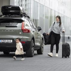 a woman and child walking down the street with luggage