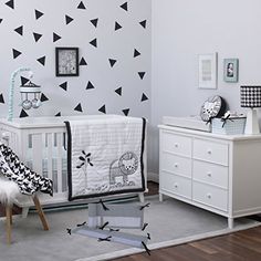 a baby's room decorated in black and white with triangles on the wall behind it