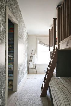 there is a ladder in the room next to the bunk bed and bookshelf