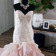 a wedding dress on display in front of a mannequin wearing a necklace and earrings