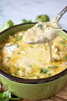 broccoli and cheese dip being scooped from a green casserole dish