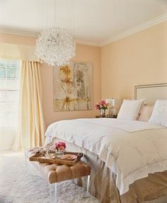 a bed room with a neatly made bed and a chandelier hanging from the ceiling