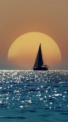 a sailboat in the ocean at sunset