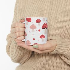 a woman holding a coffee mug with mushrooms on it