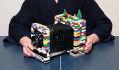 a person sitting at a table with a camera and some legos