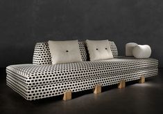 a black and white couch with two pillows on it's back legs, in front of a dark wall