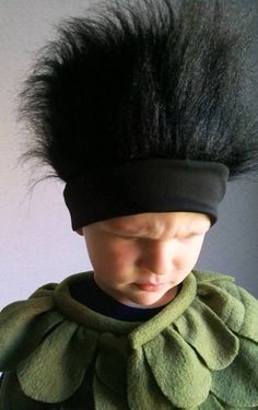 a young boy wearing a green costume with black hair