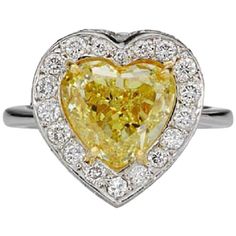 a yellow diamond heart shaped ring with diamonds around the band and center stone in white gold