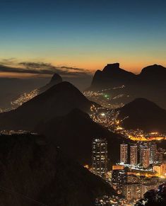 the city lights are lit up at night in this view from the top of a mountain