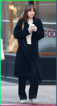 a woman walking down the street while holding a cup