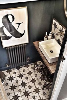 a bathroom with black and white tiles on the floor, sink and radiator