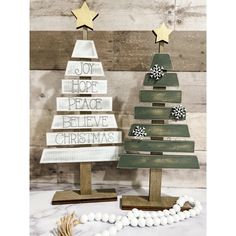 two wooden christmas trees sitting next to each other on top of a white and brown table