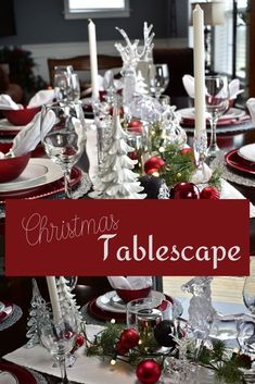 a christmas table setting with red and white plates, silverware and candlesticks