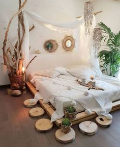 a bed with white sheets and pillows on top of wooden slices in front of a window