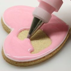 a pink cookie with a knife sticking out of the icing on top of it