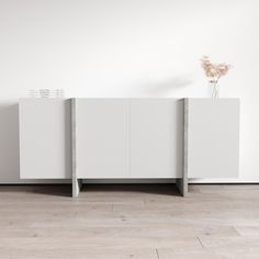 a vase with flowers sitting on top of it next to two white cabinets in a room