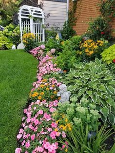 a garden filled with lots of flowers next to a house