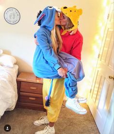 two people in winnie the pooh costumes kissing each other while standing next to a bed