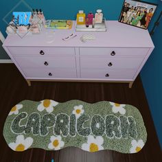 a dresser with personalized items on it in front of a blue wall and wooden floor