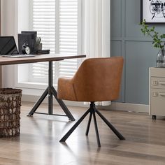 a brown chair sitting on top of a wooden floor next to a table with a laptop