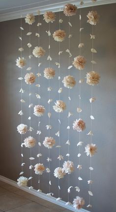 paper flowers are hanging from the ceiling in front of a wall with white and pink petals