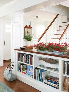 a book shelf filled with lots of books next to a stair case covered in flowers