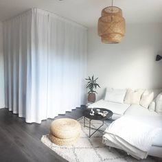 a living room with white furniture and curtains