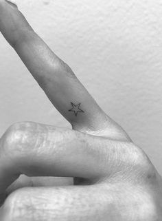 a small star tattoo on the left side of the finger is shown in black and white