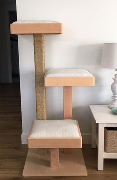 a cat tree in the corner of a living room with a lamp on top of it