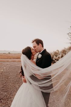 a bride and groom kissing in the desert