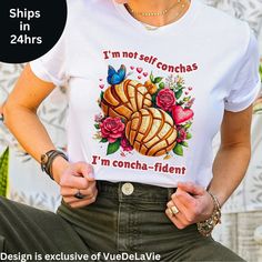 I'm not self conchas I'm concha-fident Unisex Jersey Short Sleeve Tee.  This classic unisex jersey short sleeve tee fits like a well-loved favorite. Soft cotton and quality print make users fall in love with it over and over again. These t-shirts have-ribbed knit collars to bolster shaping. The shoulders have taping for better fit over time. Dual side seams hold the garment's shape for longer.  .: 100% Airlume combed and ringspun cotton (fiber content may vary for different colors) .: Light fabr Self Conchas, Mexican Pan Dulce, Food Pun, Hispanic Food, Food Puns, Trendy Shirts, Shirt Price, Cotton Fiber, Favorite Outfit