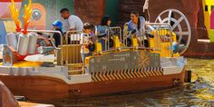 people are riding on a boat that is floating in the water at an amusement park