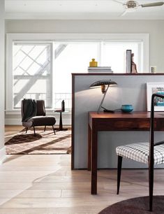 a desk with a lamp and chair in front of a window on the floor next to it