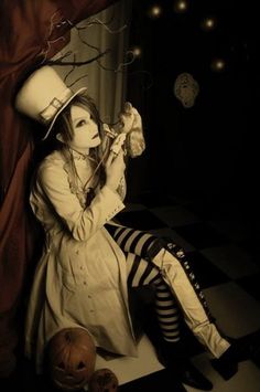 a woman sitting on the floor with her legs crossed wearing a top hat and striped stockings