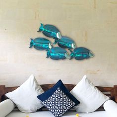 a bed with white pillows and blue fish on the wall above it, in a bedroom