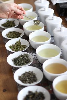 several white bowls filled with different types of tea