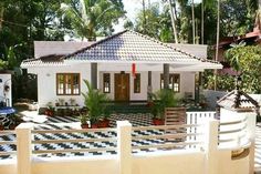 a white house with black and white checkered tile on the front yard, surrounded by greenery