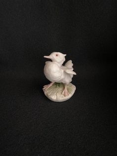 a white bird figurine sitting on top of a black surface