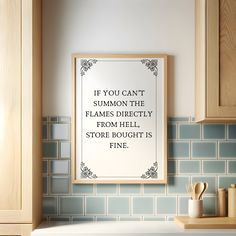 a framed poster hanging on the wall above a sink in a kitchen with blue tiles