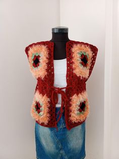 a mannequin wearing a red crocheted vest with orange and pink flowers