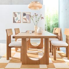 a wooden table with four chairs and a vase on it in a room that has checkered flooring