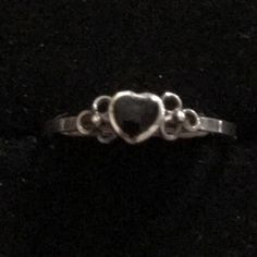 a silver ring with a black heart on it's center and two hearts in the middle