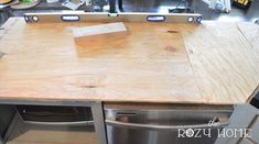 a kitchen counter being constructed with wood planks and metal appliances in the back ground